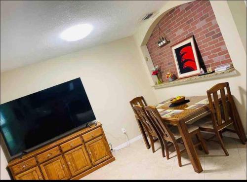 a dining room with a table and a flat screen tv at Tutul House in Tampa