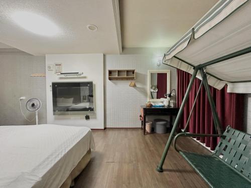 a bedroom with a bed and a television in it at 荷蘭洋行-寵物友善塩水燈會井仔腳塩田 in Xuejia
