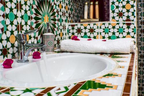 a bathroom with a sink and a tile wall at Le Petit Riad Maison d'hôtes in Ouarzazate