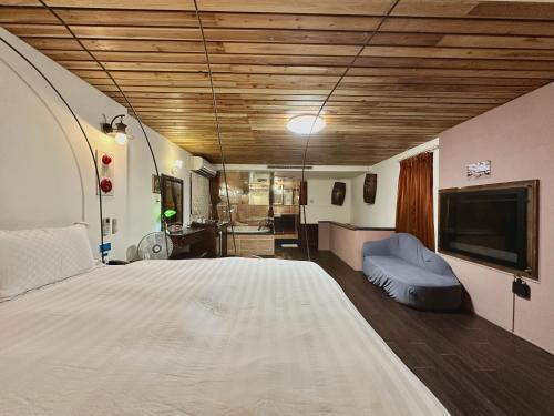 a bedroom with a large bed and a tv at 荷蘭洋行-寵物友善塩水燈會井仔腳塩田 in Xuejia