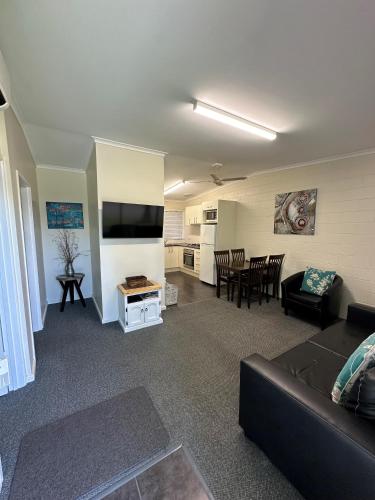 Una sala de estar con un sofá, un televisor y una mesa. en The Silver Bream Motel & Self Contained Units, en Mallacoota