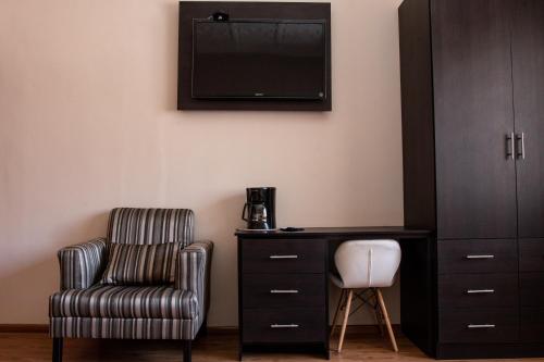 a bedroom with a chair and a desk and a television at Hotel San Benito Cuenca in Cuenca