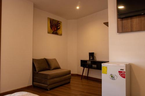 a living room with a chair and a refrigerator at Hotel San Benito Cuenca in Cuenca