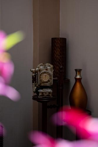 a clock sitting on a table next to a vase at Hotel San Benito Cuenca in Cuenca