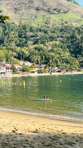 a dog swimming in the water on a surfboard at GUEST HOUSE Floresta Mar in Angra dos Reis