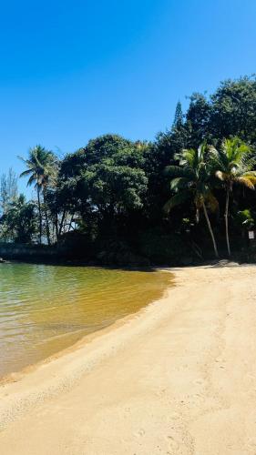 a sandy beach with palm trees in the background at GUEST HOUSE Floresta Mar in Angra dos Reis