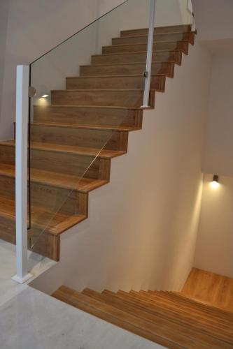 a staircase with glass railings and wood treads at Apartamentos GADIR CENTRO in Cádiz