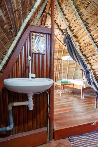 a bathroom with a sink in a thatched roof at Coin Sauvage in Ambatozavavy