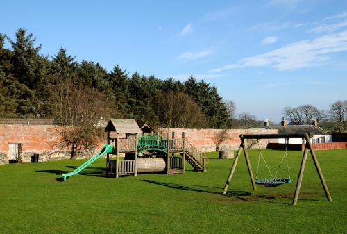 a playground with a slide and a swing at Kilconquhar Castle Estate in Kilconquhar