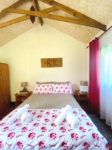 a bedroom with a large bed with red and white sheets at Cabañas Keihana Rapa Nui in Hanga Roa