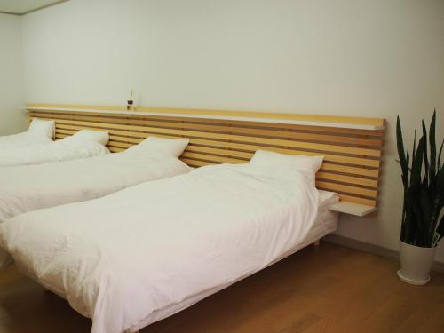 two beds with white sheets in a bedroom at ゲストハウスサンパティオ in Shingu