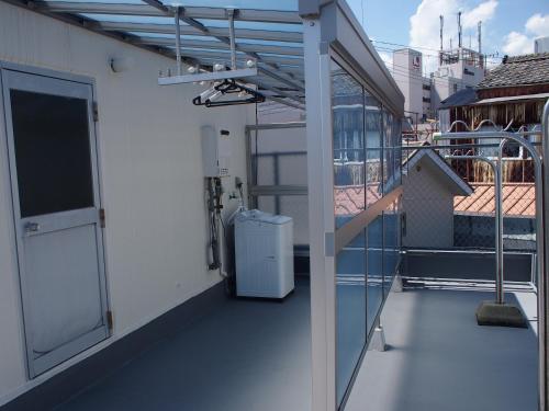 a balcony with an open door and a refrigerator at ゲストハウスサンパティオ in Shingu