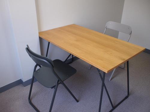 a wooden table and two chairs in a room at ゲストハウスサンパティオ in Shingu