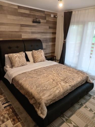 a bedroom with a large bed with a wooden wall at Casa Vis Bran in Bran