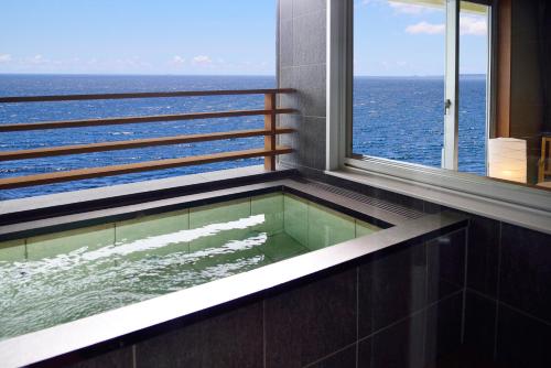 a bath tub with a view of the ocean at Kamogawa Grand Hotel in Kamogawa