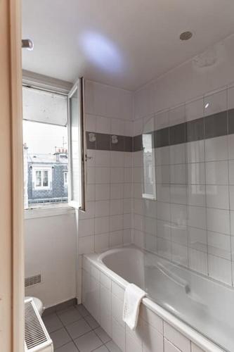 La salle de bains blanche est pourvue d'une baignoire et d'une fenêtre. dans l'établissement Charmant Duplex - Porte de Versailles- Paris -4PAX, à Paris