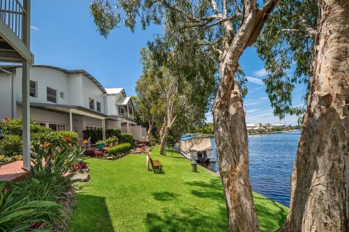 a house with a lawn next to the water at Noosa Entrance Waterfront Resort in Noosaville