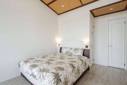 a bedroom with a bed in a room with white walls at Hale Kotsubo KARAOKE&SPA in Zushi
