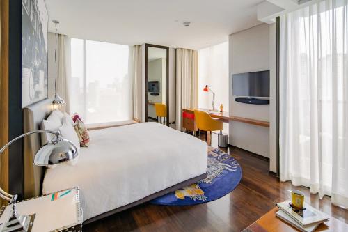a hotel room with a large bed and a desk at Hotel Indigo Bangkok Wireless Road by IHG in Bangkok