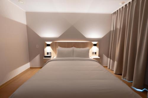 a large white bed in a room with two lamps at Le comte bleu in Pyeongchang 