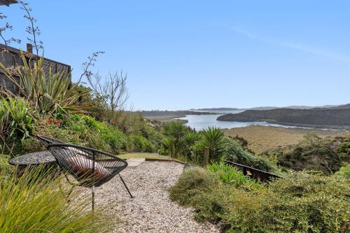 a chair sitting on a path next to a river at Sunrise Lookout - Paihia Holiday Home in Haruru