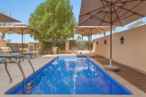 a swimming pool with umbrellas and a patio with a pool at Kempinski Hotel & Residences Palm Jumeirah in Dubai
