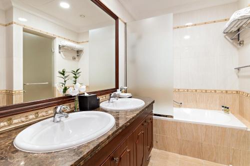 a bathroom with two sinks and a tub and a mirror at Kempinski Hotel & Residences Palm Jumeirah in Dubai