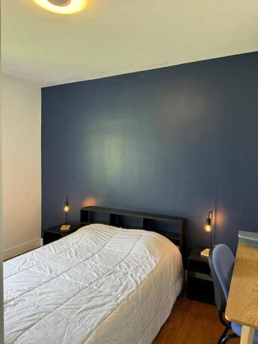 une chambre avec un lit et un mur bleu dans l'établissement Appartement calme avec vue à 20 minutes de la gare, à Saint-Égrève