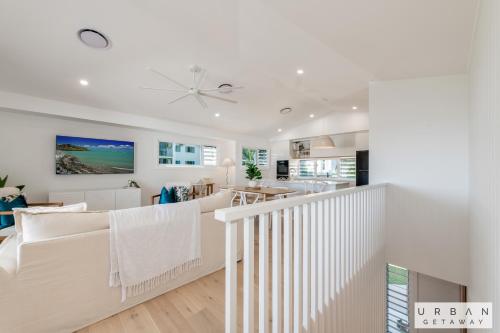 a living room with white furniture and a staircase at Bargara Coastal Luxe Aircon, Outside Pet, Sleeps 8 in Bargara