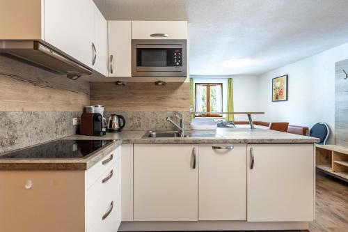 a kitchen with white cabinets and a microwave at Apartment Anton Huter in Sankt Anton am Arlberg
