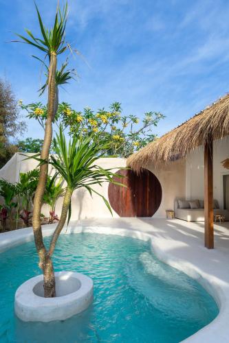a pool with two palm trees in a villa at Wellhouse Villas in Nusa Lembongan