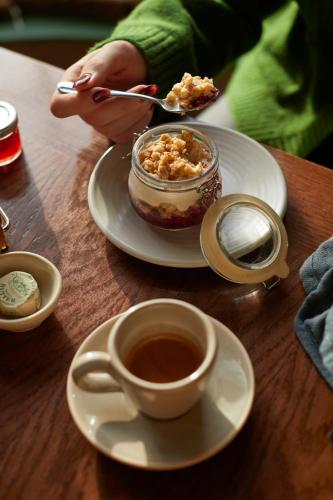 a person eating food on a table with a cup of coffee at The White Horse - A Heartwood Inn in Dorking