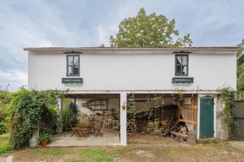 a white house with green shutters and a patio at C Vilamide in Parada de Achas