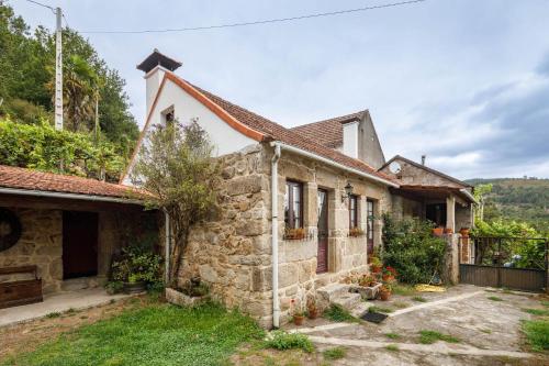 an old stone house with a garden and a fence at C Vilamide in Parada de Achas