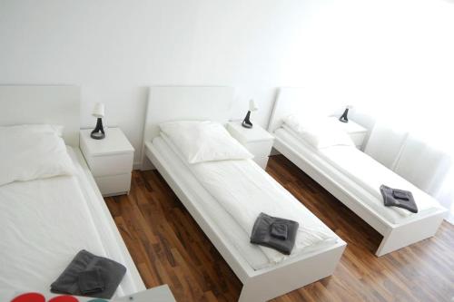 three beds in a room with white walls and wooden floors at Moderne 3-Zimmer-Wohnung für bis zu 7 Personen in Friesenheim