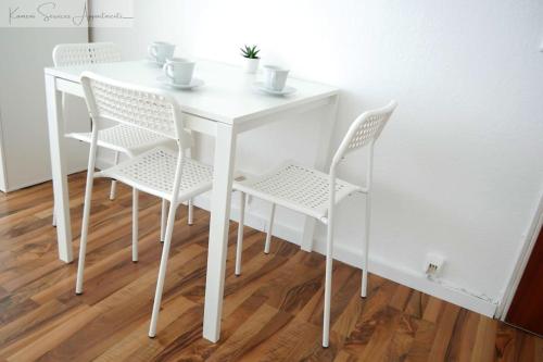 a white dining room table with four white chairs at Moderne 3-Zimmer-Wohnung für bis zu 7 Personen in Friesenheim