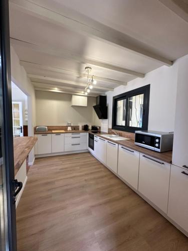 Il comprend une grande cuisine avec des placards blancs et du parquet. dans l'établissement maison du phare, à Sémussac