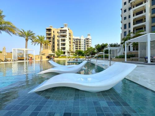 two white sculptures sitting next to a swimming pool at MegaLuxury Flat Resort, Amazing Pool, Burj direct View in Dubai