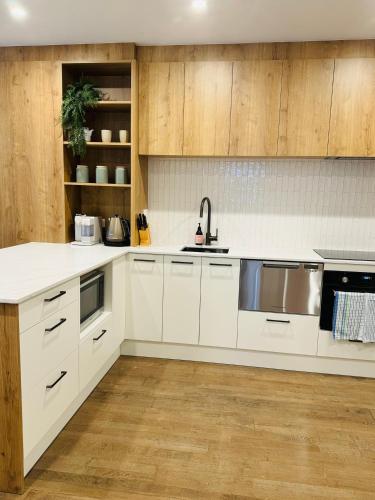 a kitchen with white cabinets and a sink at Beach Front Dream Lifestyle in Auckland