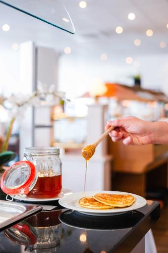 a person pouring syrup onto a plate of food at Hotel des Nordens Flensburg Wellness & Spa in Flensburg