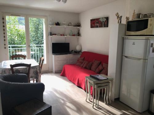 a living room with a red couch and a microwave at Les Jardins du Casino T2 bis- 4 personnes-Tarif cures 700 euros in Luchon