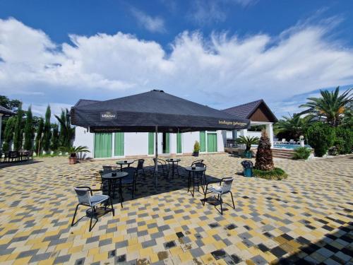 a patio with chairs and tables and an umbrella at White villas in Batumi in Batumi
