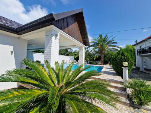 a house with a palm tree in front of a swimming pool at White villas in Batumi in Batumi