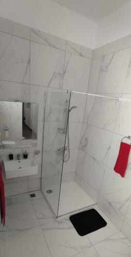 a white bathroom with a shower and a sink at Charming Townhouse - Steps from Waterfront in Marsaxlokk