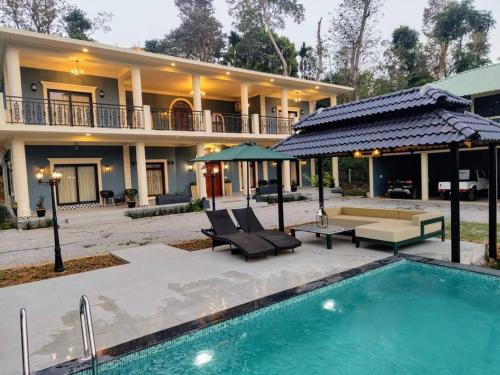 a house with a swimming pool in front of a house at Villa Forever Coorg in Madikeri