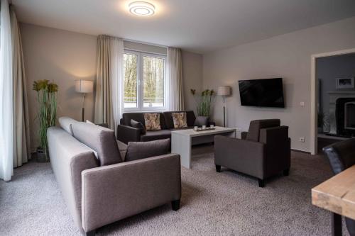 a living room with a couch and chairs and a tv at Hotel des Nordens Flensburg Wellness & Spa in Flensburg