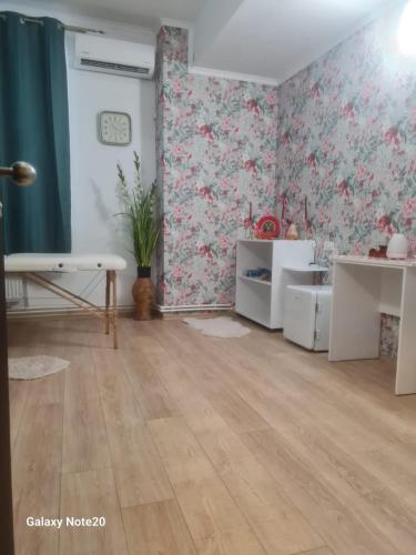 a living room with floral wallpaper and wooden floors at Camere de inchiriat Nys 2 stele in Iaşi