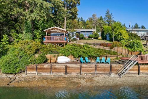 a yard with chairs and a house next to the water at Captain's Retreat in Shelton