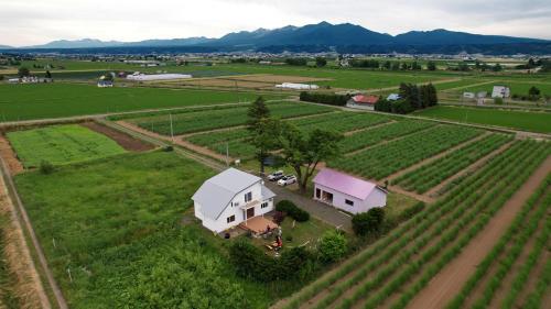 an aerial view of a farm with a white house at HOKKAIDO VILLA e2 in Nakafurano