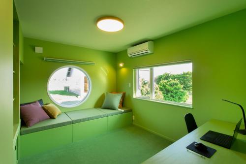 a green room with a bench and a window at HOKKAIDO VILLA e2 in Nakafurano